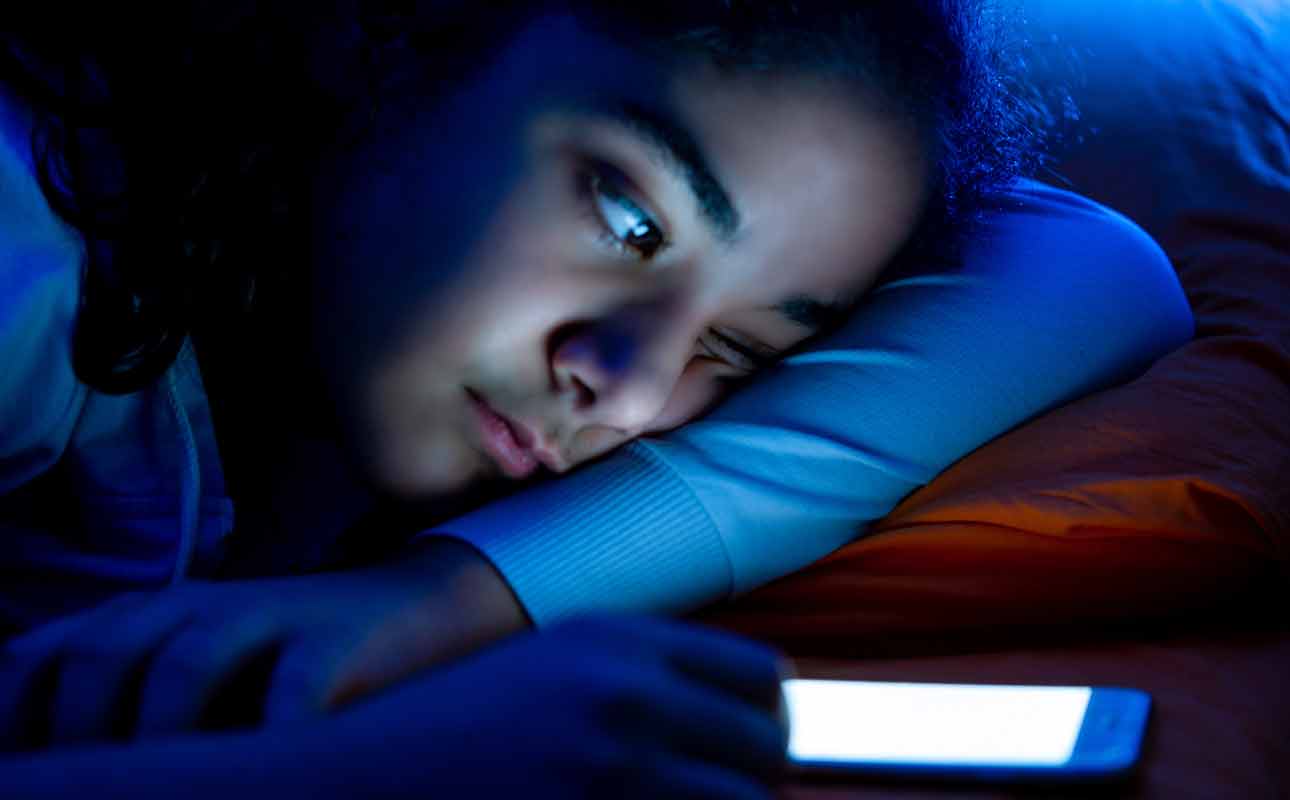 Woman looking at mobile phone in bed